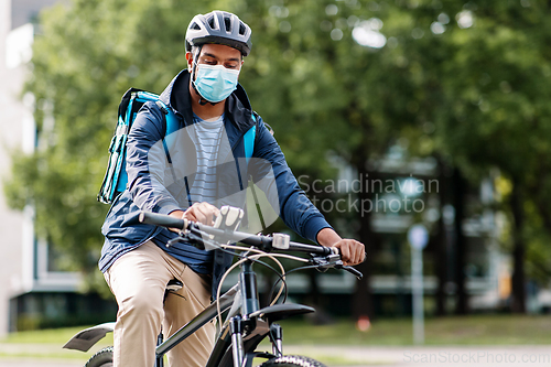 Image of delivery man in mask with smatphone riding bicycle