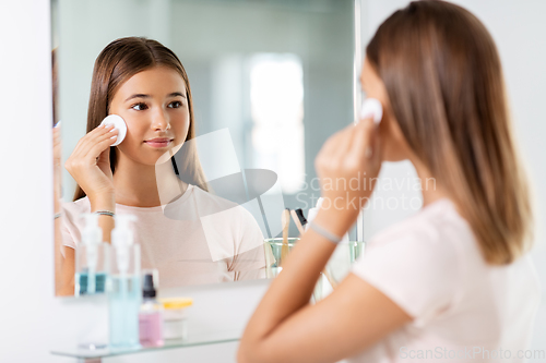 Image of teenage girl cleaning face skin with cotton disc