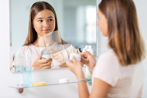 Image of teenage girl with moisturizer at bathroom