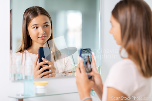 Image of teenage girl looking in mirror and taking selfie