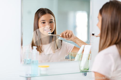 Image of teenage girl with toothbrush brushing teeth