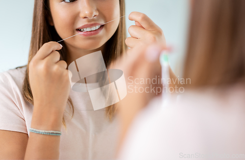 Image of teenage girl with floss cleaning teeth at bathroom