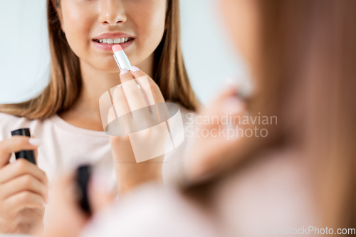 Image of teenage girl applying lipstick at bathroom