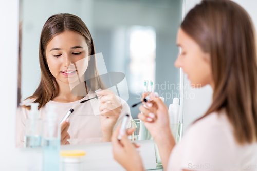 Image of teenage girl applying mascara at bathroom