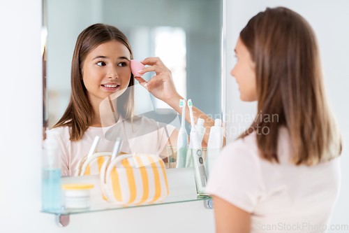 Image of teenage girl applying foundation to face