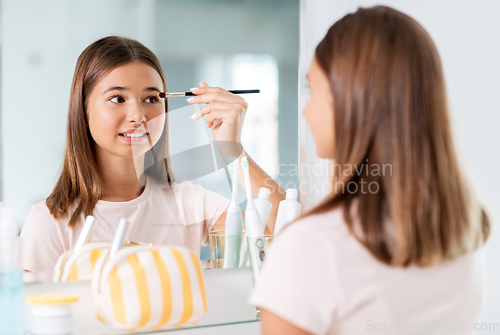 Image of teenage girl applying eye shadow at bathroom