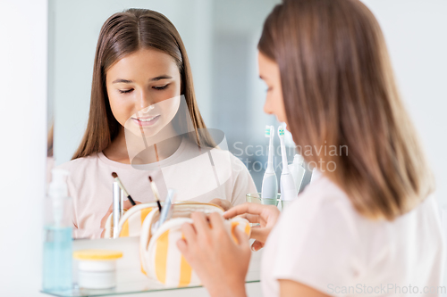 Image of teenage girl with cosmetic bag at bathroom