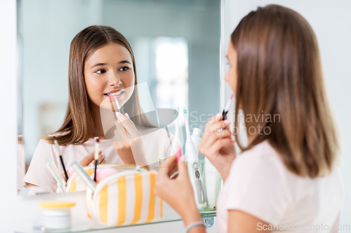 Image of teenage girl applying lip gloss at bathroom