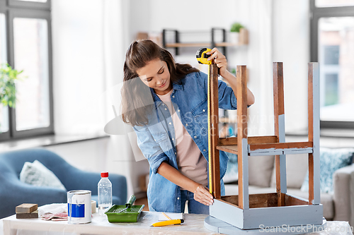 Image of woman with ruler measuring table for renovation