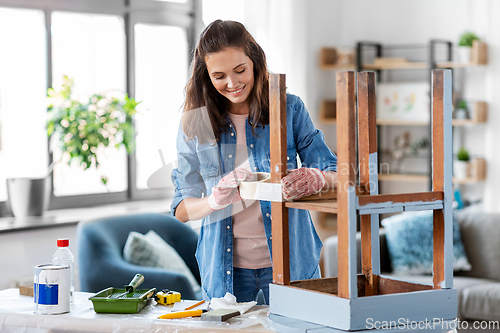 Image of woman sticking masking tape to table for repaint