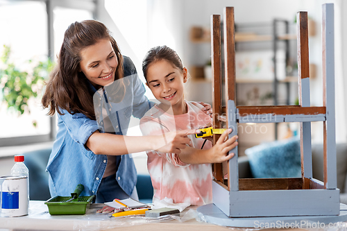 Image of mother and daughter with ruler measuring old table