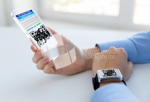 Image of hands with virtual immunity passport on smartphone