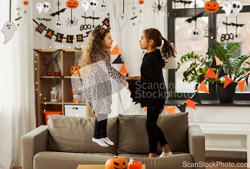 Image of girls in halloween costumes jumping on sofa