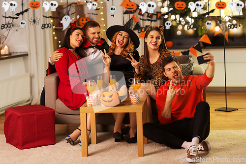 Image of happy friends in halloween costumes taking selfie