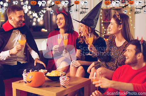 Image of happy friends in halloween costumes at home party