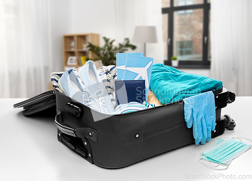 Image of travel bag packed with clothes, gloves and masks