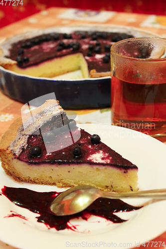 Image of Piece of pie with bilberry on the plate and cup of tea