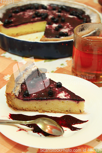 Image of Piece of pie with bilberry on the plate and cup of tea