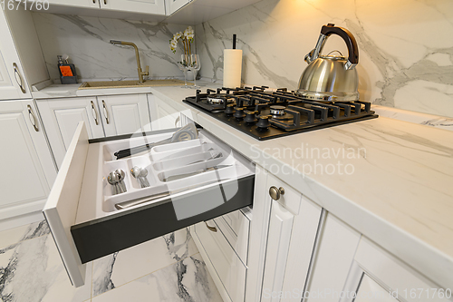 Image of Open drawers with kitchenware at modern white kitchen