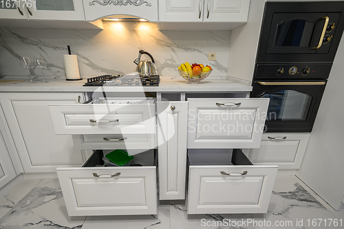 Image of Open drawers with kitchenware at modern white kitchen