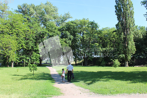 Image of father with his daughter have a rest in park with big trees