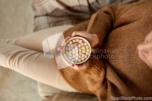 Image of woman holding mug of hot chocolate and marshmallow