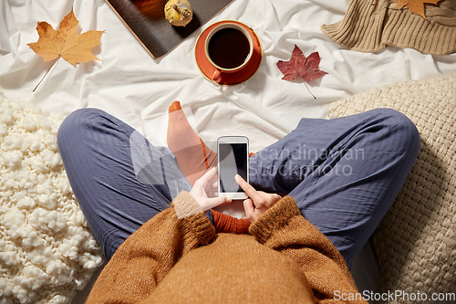 Image of woman with smartphone at home in autumn