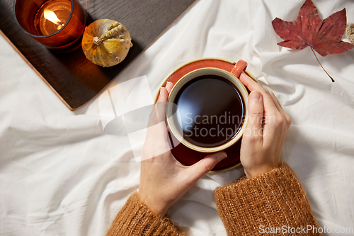 Image of hands of woman with cup of coffee in autumn