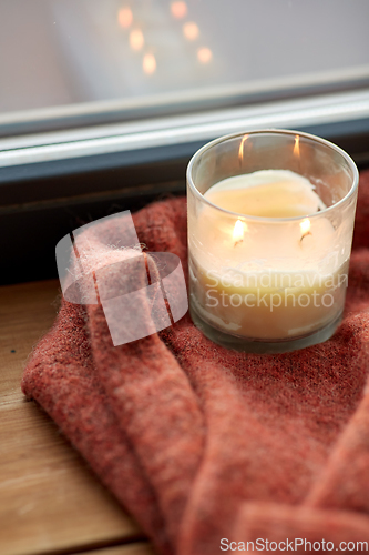 Image of woolen sweater and candle burning on window sill