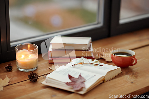 Image of book, coffee and candle on window sill in autumn