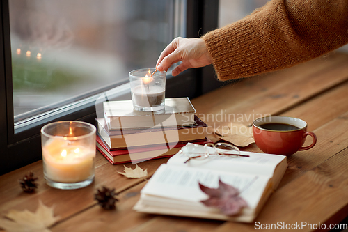 Image of hand with match lighting candle on window sill