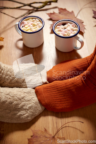 Image of couple of feet in socks, coffee and autumn leaves