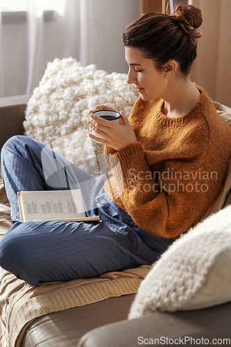 Image of woman drinking coffee and reading book at home