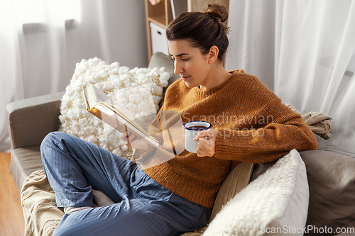 Image of woman drinking coffee and reading book at home