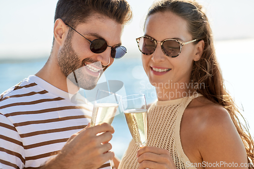 Image of happy couple drinking champagne on summer beach