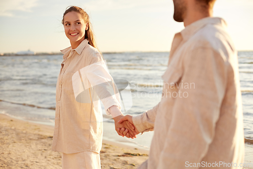 Image of happy couple holding hands on summer beach