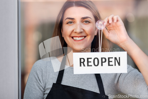 Image of happy woman hanging reopen banner to door glass