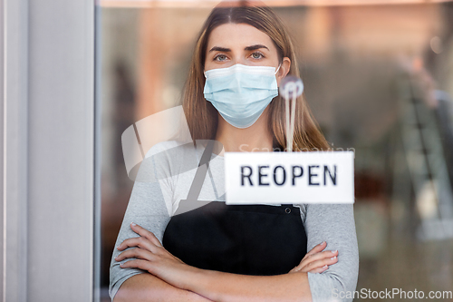 Image of woman in mask with reopen banner on door glass