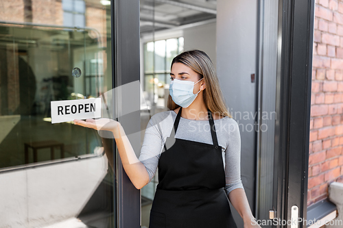 Image of woman in mask showing reopen banner on door glass