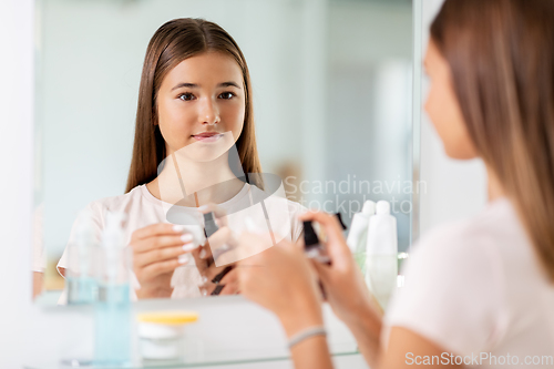 Image of teenage girl applying lotion to cotton disc