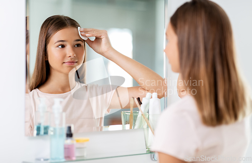 Image of teenage girl cleaning face skin with cotton disc