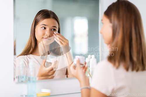 Image of teenage girl with moisturizer at bathroom