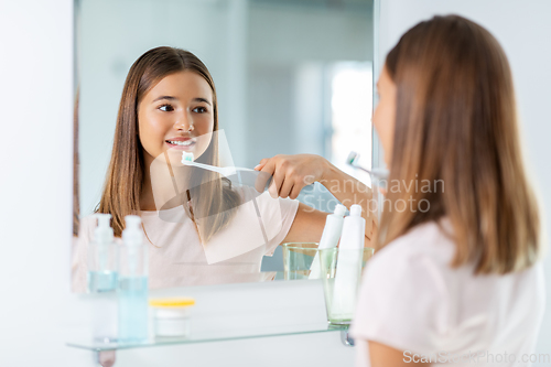 Image of teen girl with electric toothbrush brushing teeth