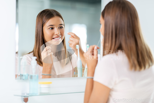 Image of teenage girl with floss cleaning teeth at bathroom