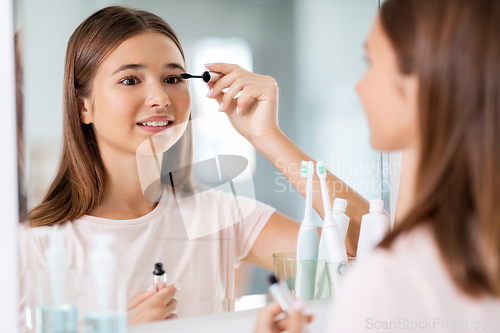 Image of teenage girl applying mascara at bathroom