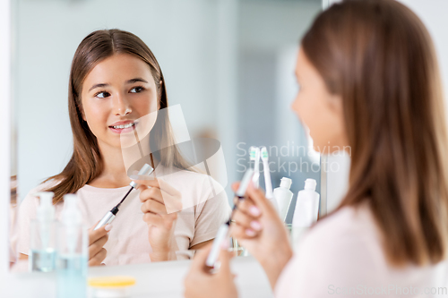 Image of teenage girl applying mascara at bathroom