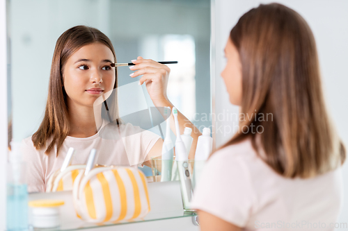 Image of teenage girl applying eye shadow at bathroom