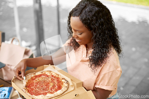 Image of african student girl eating takeaway pizza in city