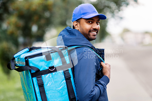 Image of happy smiling indian delivery man with bag in city