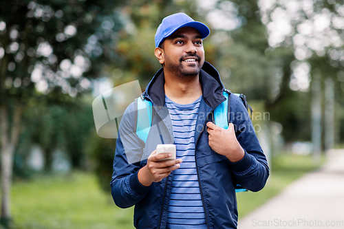 Image of smiling indian delivery man with bag and phone